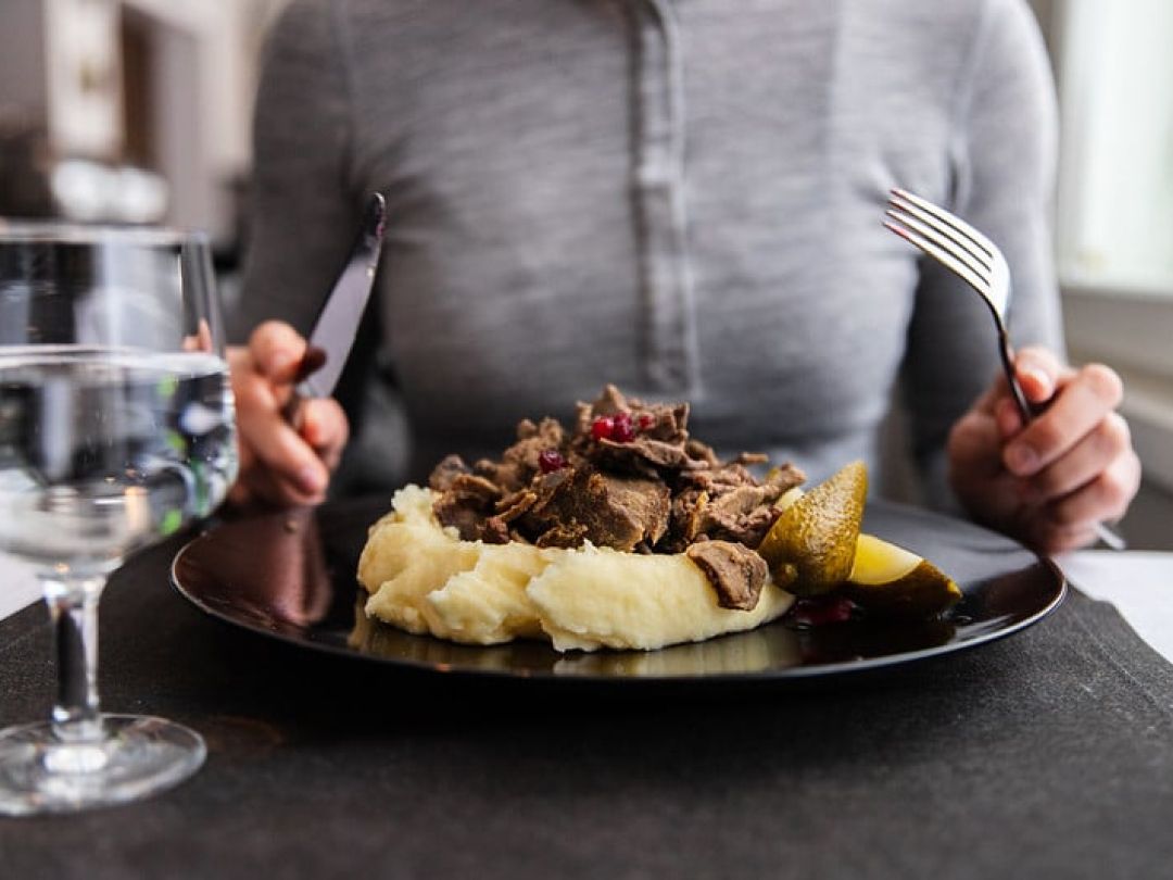 Person about to eat a dish of mashed potatoes with meat and garnish.