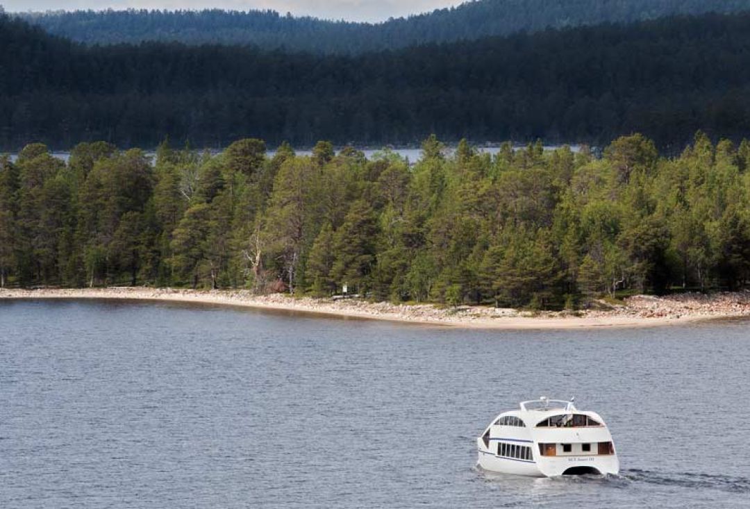 Lake Inari Cruise traveling through the lake near a sandy beach.