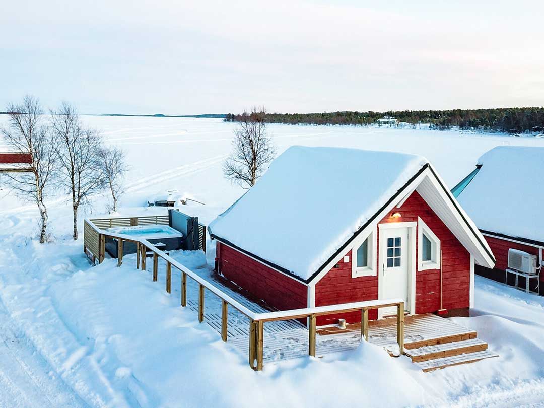 Aurora sauna from outside in snowy scenery. Hot tub on the yard.