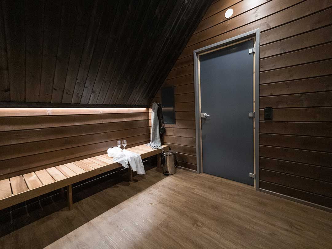 Sauna interior dressing room area with wooden benches and towel placed on bench.