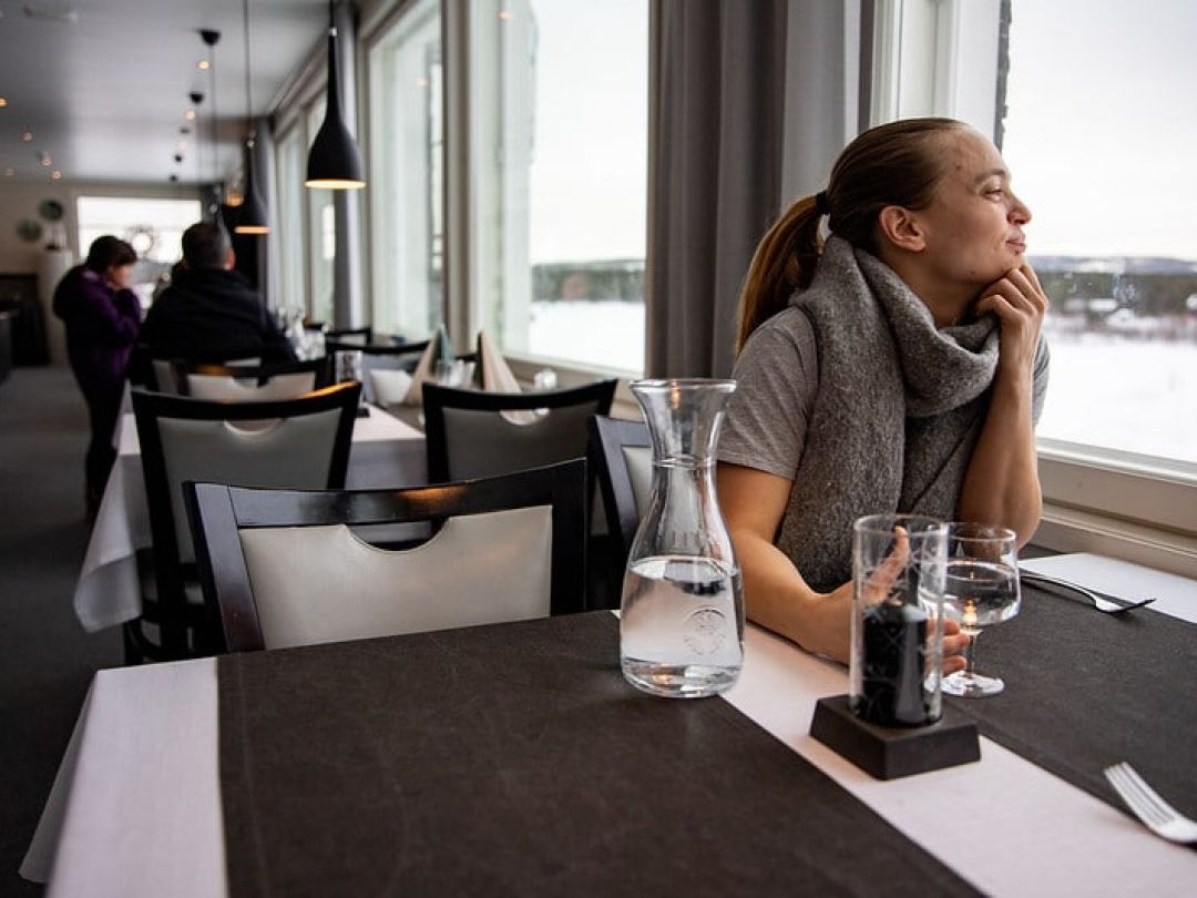 Woman sitting at a restaurant table looking thoughtfully out the window.