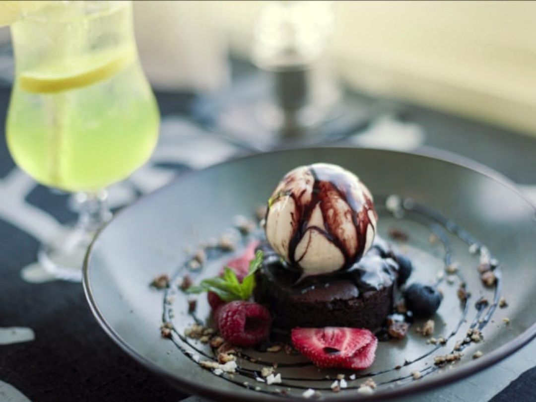 Dessert of ice cream with berries and chocolate sauce on a plate.