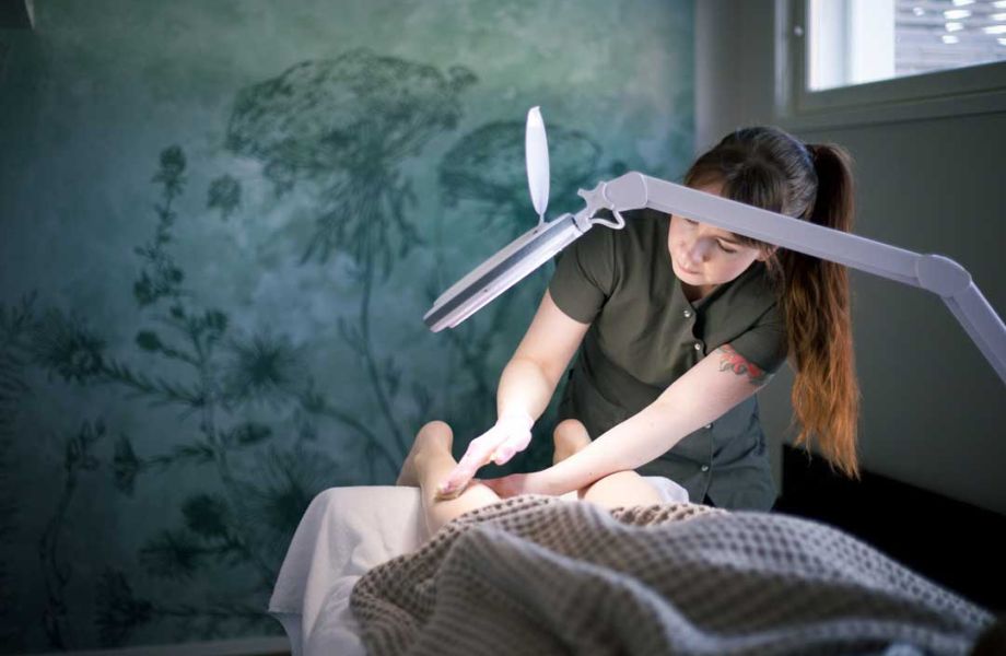 A massager massaging calf in peaceful room under spotlight.
