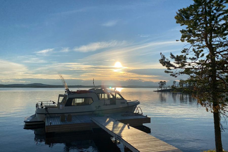 Small yacht end of a wooden pier. Big lake on sunrise.
